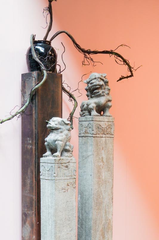 Chinese Fu Dog palen met leeuwenkoppen gemaakt van steen, met een oude zwarte pot versierd met vaantjes