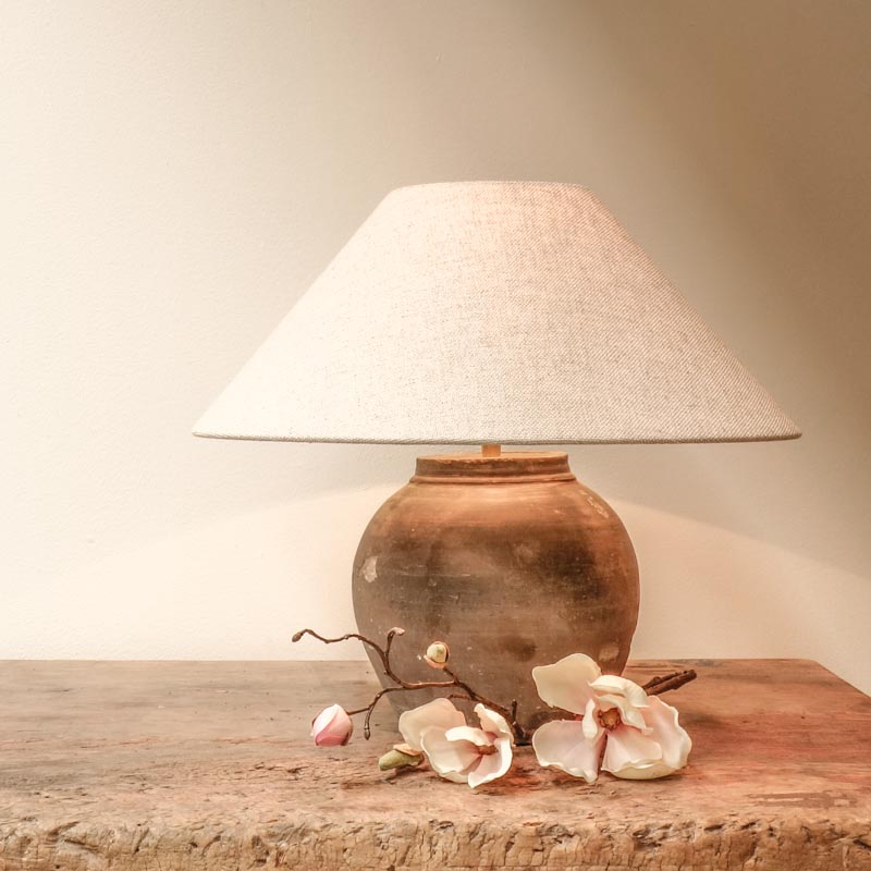 Old country style Chinese ceramic pot which is repurposed into a lamp, with a decorative flower on the front
