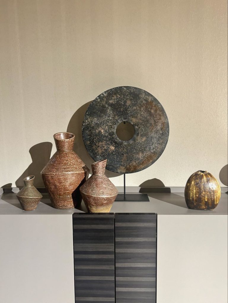 Selection of weathered jars and a decorative bi-disk at Salone Del Mobile 2024.
